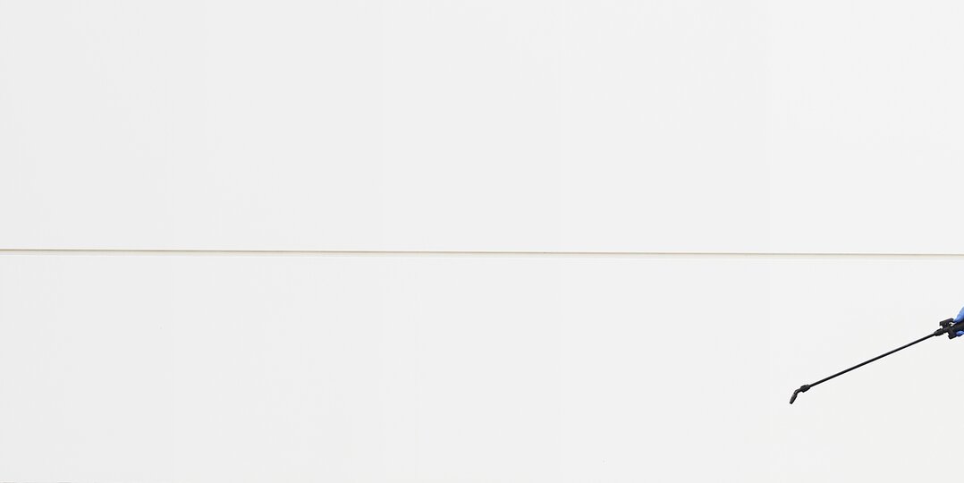 Pracownik w stroju ochronnym w trakcie dezynfekcji pomieszczenia